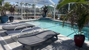 A pool area with lounge chairs and potted plants.