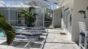 A pool area with lounge chairs and a covered patio.