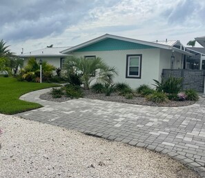 A modern house with a green roof, surrounded by a well-maintained lawn and palm trees. - 3 Master Suites-EVERYTHING is new pool home on the water (Saint James City)