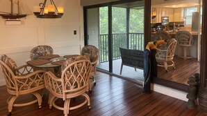 A dining area with wicker chairs and a round table, a chandelier, and a view of the outdoor deck. - 2 bed/ 2.5 bath Waterfront Condo with 2 pools and great fishing (Bokeelia)
