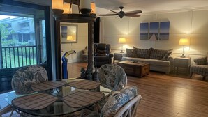 A spacious living room with a glass-top table surrounded by wicker chairs, a sofa set, and a ceiling fan. - 2 bed/ 2.5 bath Waterfront Condo with 2 pools and great fishing (Bokeelia)
