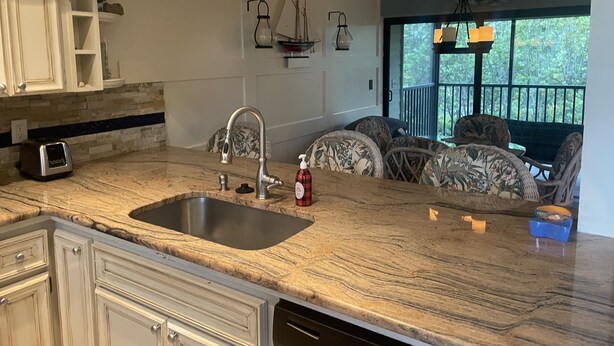 A kitchen with a granite countertop, stainless steel sink, and white cabinetry. - 2 bed/ 2.5 bath Waterfront Condo with 2 pools and great fishing (Bokeelia)