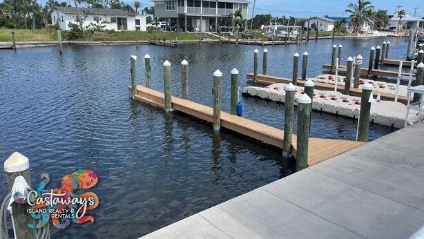 A marina with docks, a house, and a boat. - Peaceful Island Living @ The Buccaneer Condo 1BR/1 BR with pool and dock (Saint James City)