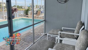 A poolside area with a view of a pool, lounge chairs, and a decorative wall piece. - Peaceful Island Living @ The Buccaneer Condo 1BR/1 BR with pool and dock (Saint James City)