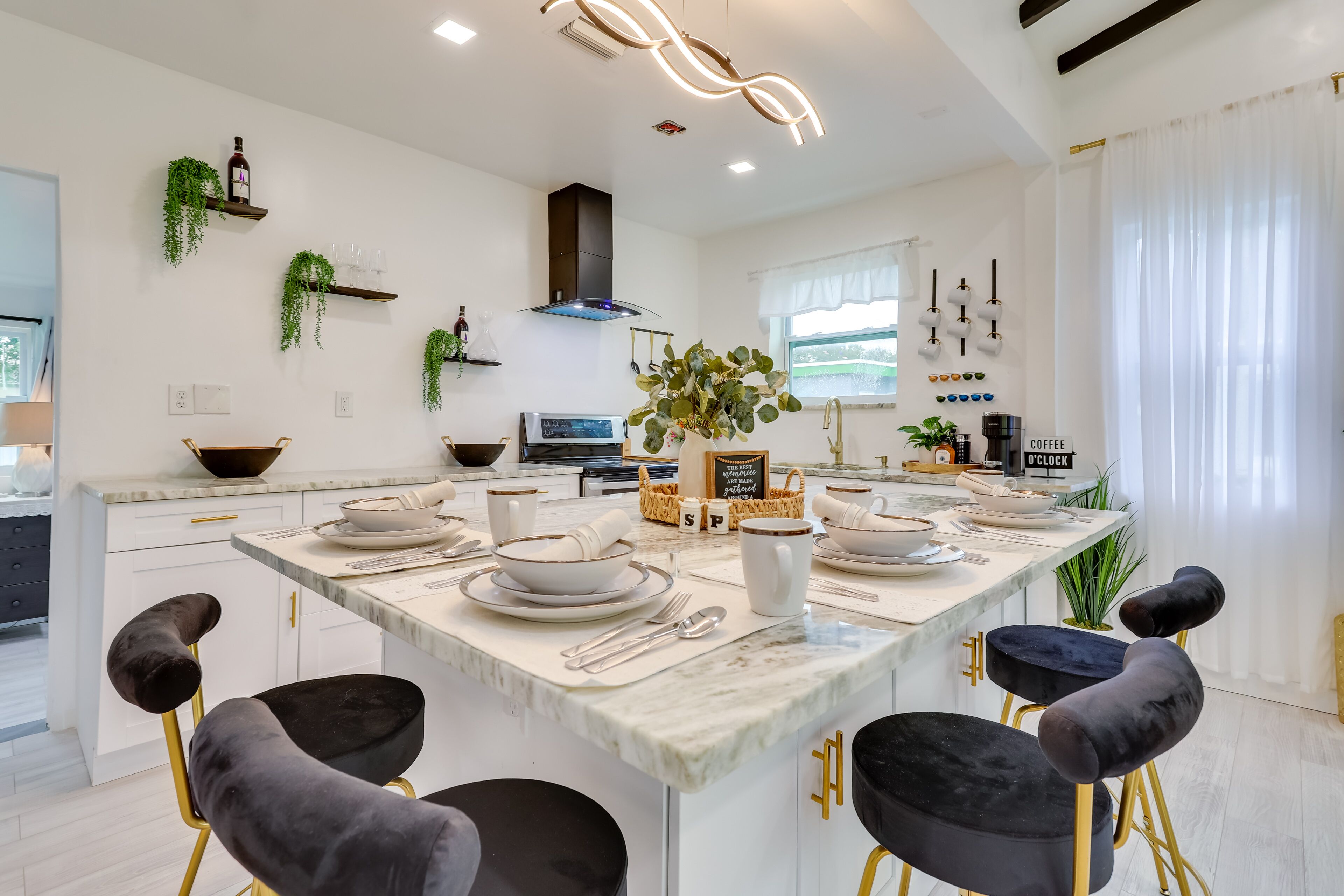 Een moderne keuken met een centraal eiland, witte kasten en zwarte stoelen.
