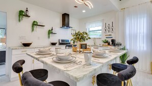 Una cocina moderna con una isla central, armarios blancos y sillas negras.