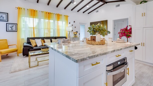 Una cocina moderna con armarios blancos, encimera de mármol y horno empotrado.