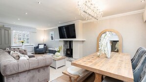 A modern living room with a sofa, a dining table, a fireplace, and a TV. - New Listing Special Discount! (Greater Manchester)