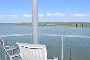 Een balkon met uitzicht op een rustig wateroppervlak en veraf gelegen land.
