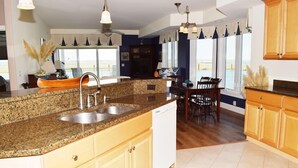 A kitchen with granite countertops, white cabinets, and a dishwasher. - Sunset Bay Villa #202- Waterfront, In Town, Pool & Gym (Chincoteague)
