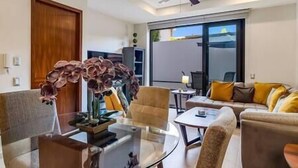 A modern living room with a ceiling fan, a sofa set, a coffee table, and a large window with a view. - A FEW BREEZY STEPS TO THE BEACH ~LUXURIOUS STAY~ (Puerto Vallarta)