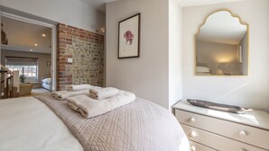A bedroom with a large bed, a dresser, a framed picture, and a mirror.