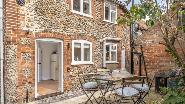 A stone house with a patio area featuring a wooden table and chairs.