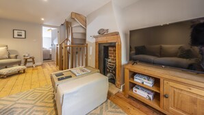 A cozy living room with a staircase, a fireplace, a sofa, and a TV.
