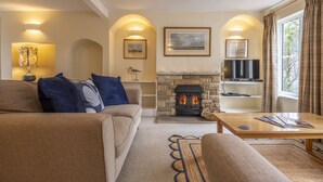A cozy living room with a fireplace, comfortable seating, and a television. - Blackhorse Cottage, Brancaster Staithe, Norfok (Brancaster Staithe)