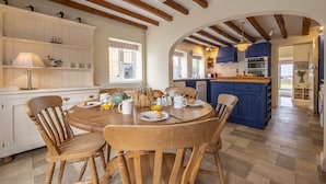 A kitchen with wooden beams, a dining table with chairs, and a blue island. - Blackhorse Cottage, Brancaster Staithe, Norfok (Brancaster Staithe)