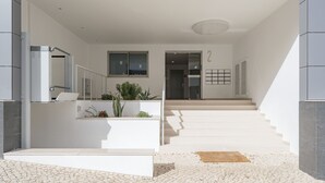 Een modern interieur met een trap naar een tweede verdieping, een receptiebalie en een paneel voor bediening aan de muur.