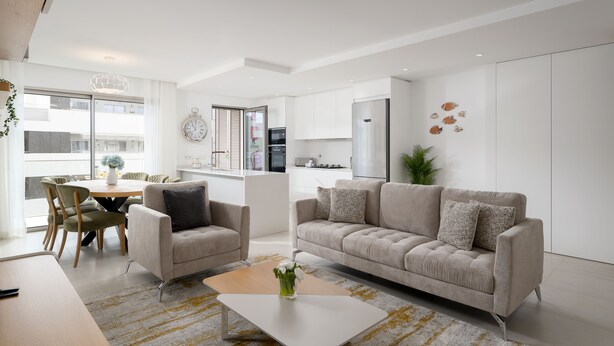 Een moderne woonkamer met een bank, fauteuils, een salontafel en een eethoek met stoelen en een tafel.