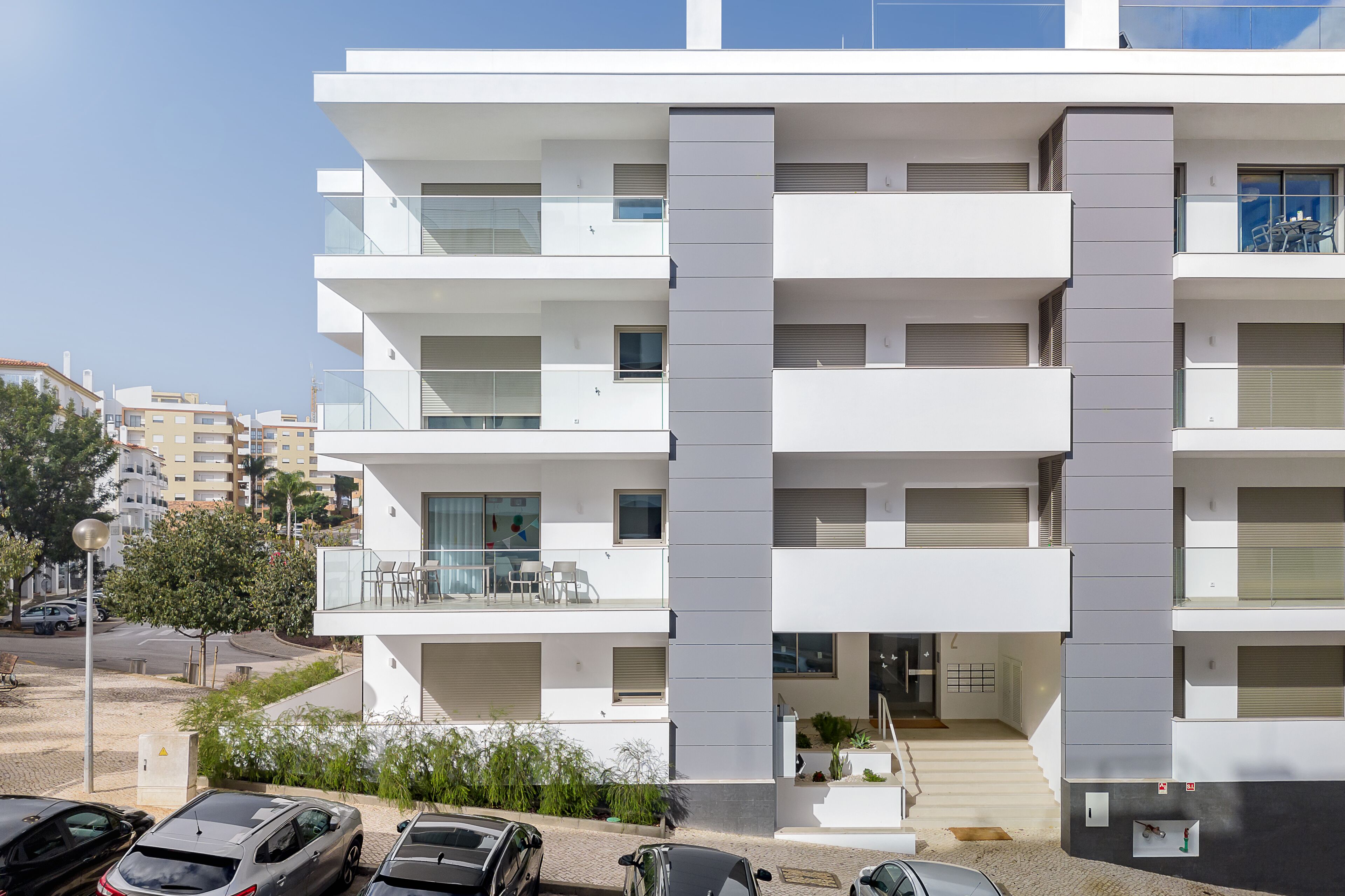 A multi-story residential building with balconies, a staircase, and a parking area.