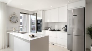 Een moderne keuken met witte kasten, roestvrijstalen apparatuur en een centraal eiland.
