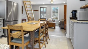 Eine moderne Küche mit Holzbalken, Edelstahlgeräten und einem Essbereich mit einem Holztisch und Stühlen.