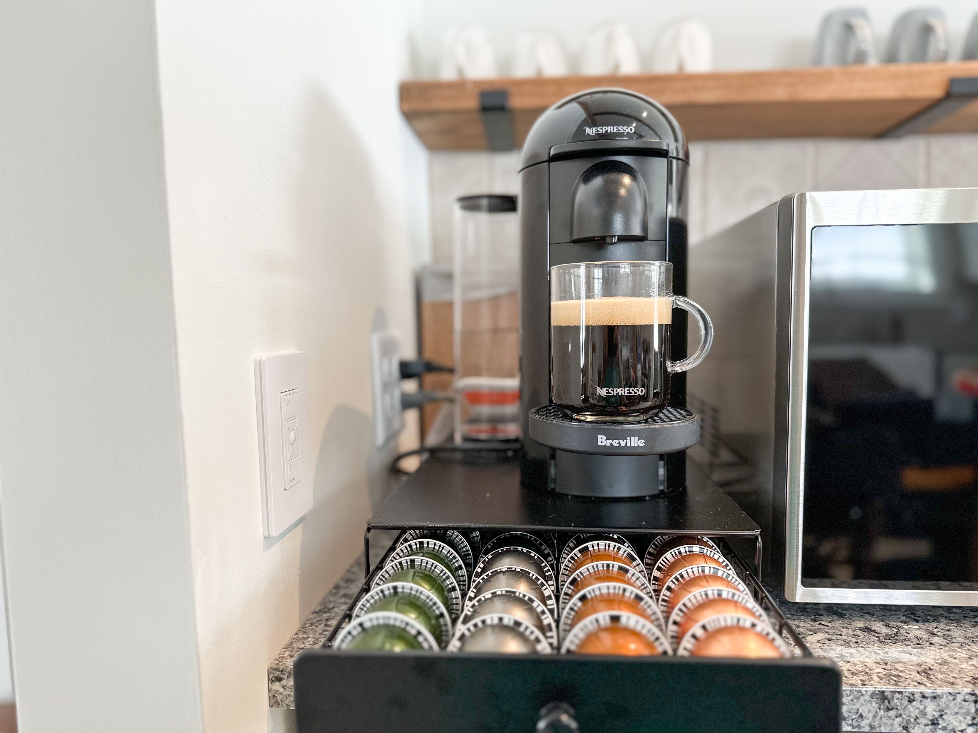 Een koffieapparaat met een kop koffie, een koffieapparaat merk en een houder voor koffiecups.