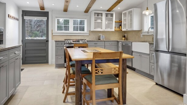 Eine moderne Küche mit Holzbalken, einem Edelstahlkühlschrank und einem Essbereich mit Holztisch und -stühlen.