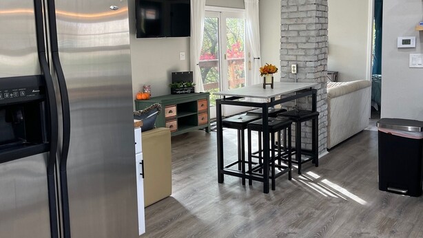 A modern kitchen with a stainless steel refrigerator, a stone pillar, and a dining area with bar stools.