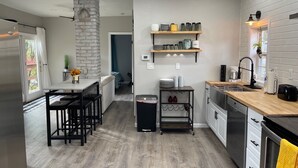 A modern kitchen with a stone accent wall, wooden flooring, and a central island with bar stools.