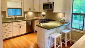 Una cocina moderna con armarios blancos, electrodomésticos de acero inoxidable y encimera verde.