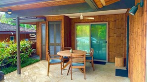 Un patio techado con una mesa y sillas de madera, un ventilador de techo y puertas correderas de vidrio.