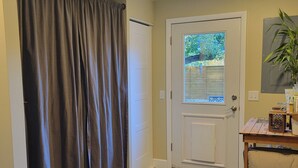 A hallway with a door, a window, a rug, and a plant.