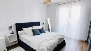 Ein modernes Schlafzimmer mit einem großen Bett, weißen Wänden und Holzböden.