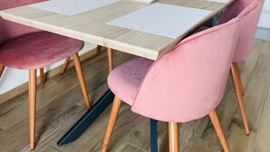 Ein Essbereich mit einem Holztisch und rosa gepolsterten Stühlen.