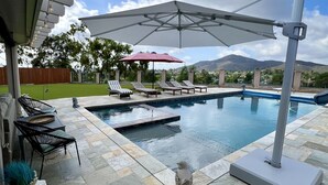 A swimming pool with lounge chairs and a pergola with string lights. - Fletcher Hills luxury, Sunset View, 4 BR, Saltwater Pool and Spa (El Cajon)