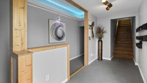 A hallway with a wooden frame, a gray wall, a staircase, and a modern light fixture. - Modern Studio Apartment in the heart of Festus (Festus)