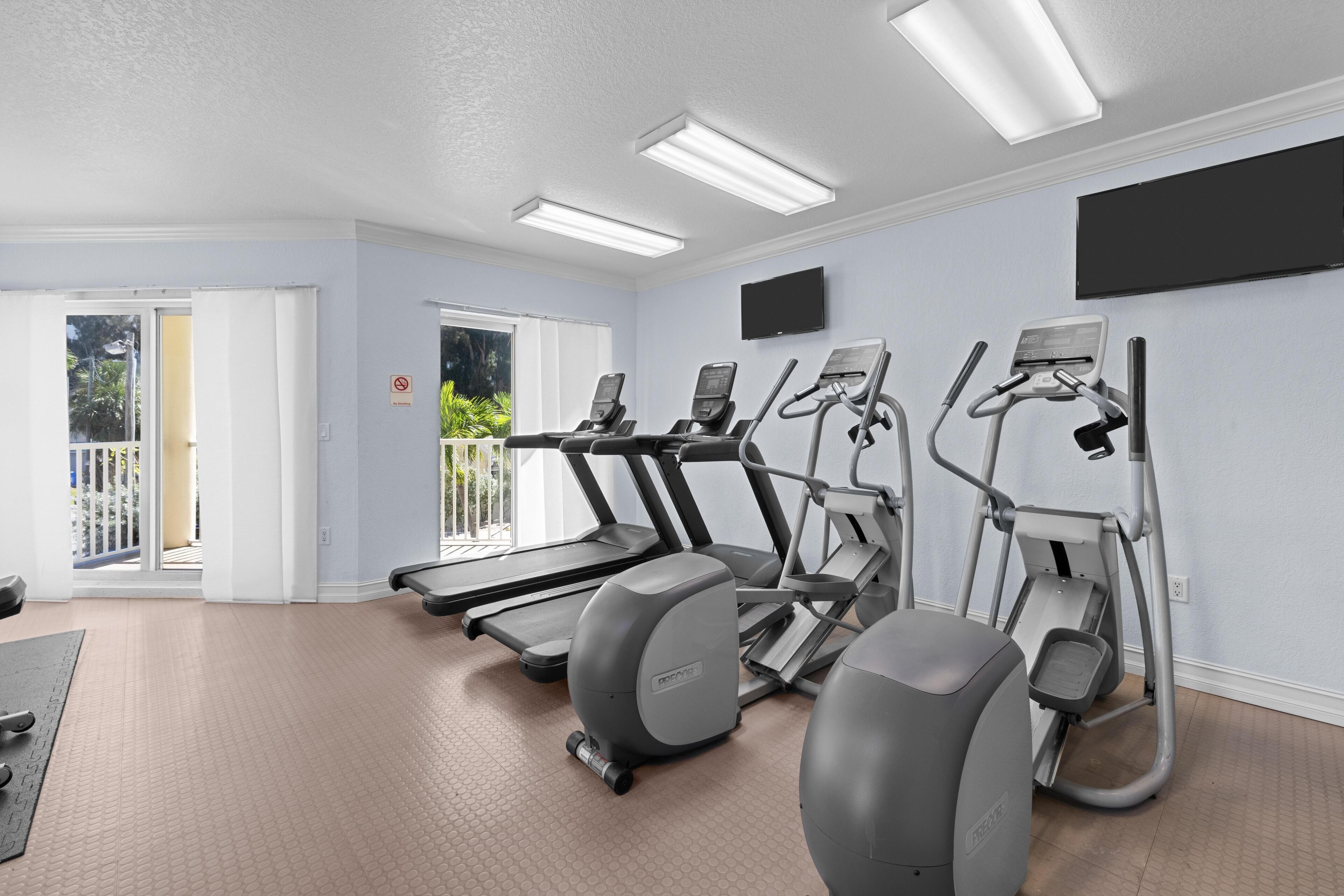 A gym with treadmills, elliptical machines, and a stationary bike.