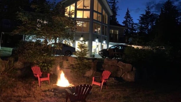 A modern house with a large glass facade, a fire pit with chairs, and a car parked in front. - Viceroy home at Soames Hill (Gibsons)