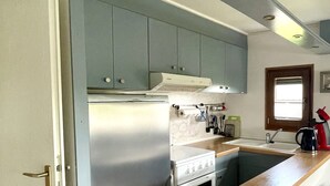 A compact kitchen with a built-in refrigerator, oven, and sink. - Mobilheim an der Ostsee, 350 m zum Strand (Heringsdorf)