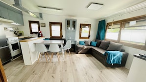 A compact living space with a kitchenette, a dining area, and a seating area with a sofa and chairs. - Mobilheim an der Ostsee, 350 m zum Strand (Heringsdorf)