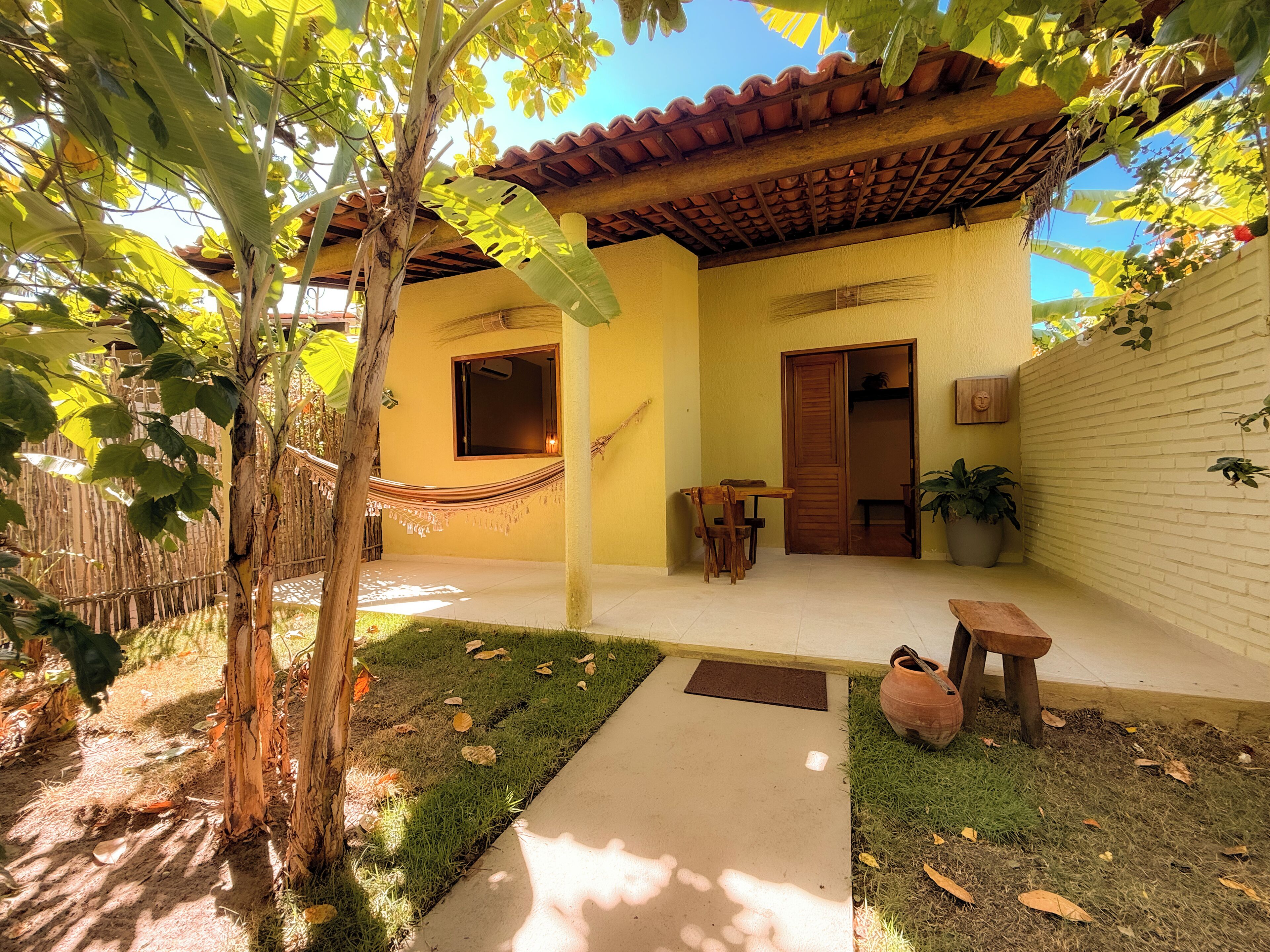 A house with a tiled roof, a wooden door, a window, and a small patio area with a table and chairs.