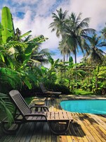Una piscina al aire libre, sombrillas, sillones reclinables de piscina