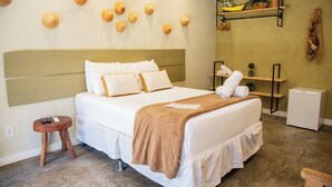 A hotel room with a bed, bedside tables, a small stool, and a wall-mounted shelf with decorative items. - Pousada kaçuá Milagres (São Miguel dos Milagres)