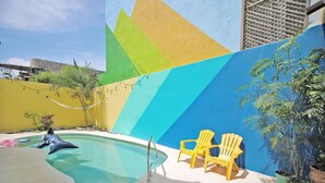 A swimming pool with a dolphin float, two yellow chairs, and potted plants. - 2BR - Fast Internet, Near Beach, Pool, King Beds, ACs (Puerto Escondido)