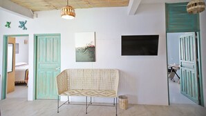 A room with a woven bench, a flat-screen TV, and a ceiling with a woven light fixture. - 2BR - Fast Internet, Near Beach, Pool, King Beds, ACs (Puerto Escondido)