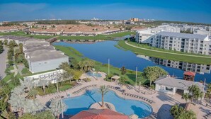 A resort with a large swimming pool, a tennis court, and a view of the surrounding buildings and water. - Special Offer! Frozen Themed Condo on the top floor lake view close to Disney  (Kissimmee)