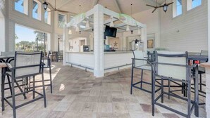 A spacious indoor area with a high ceiling, multiple seating arrangements, and a central counter with a television. - Special Offer! Frozen Themed Condo on the top floor lake view close to Disney  (Kissimmee)