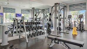 A modern gym with various exercise equipment, including dumbbells, a squat rack, and treadmills. - Special Offer! Frozen Themed Condo on the top floor lake view close to Disney  (Kissimmee)