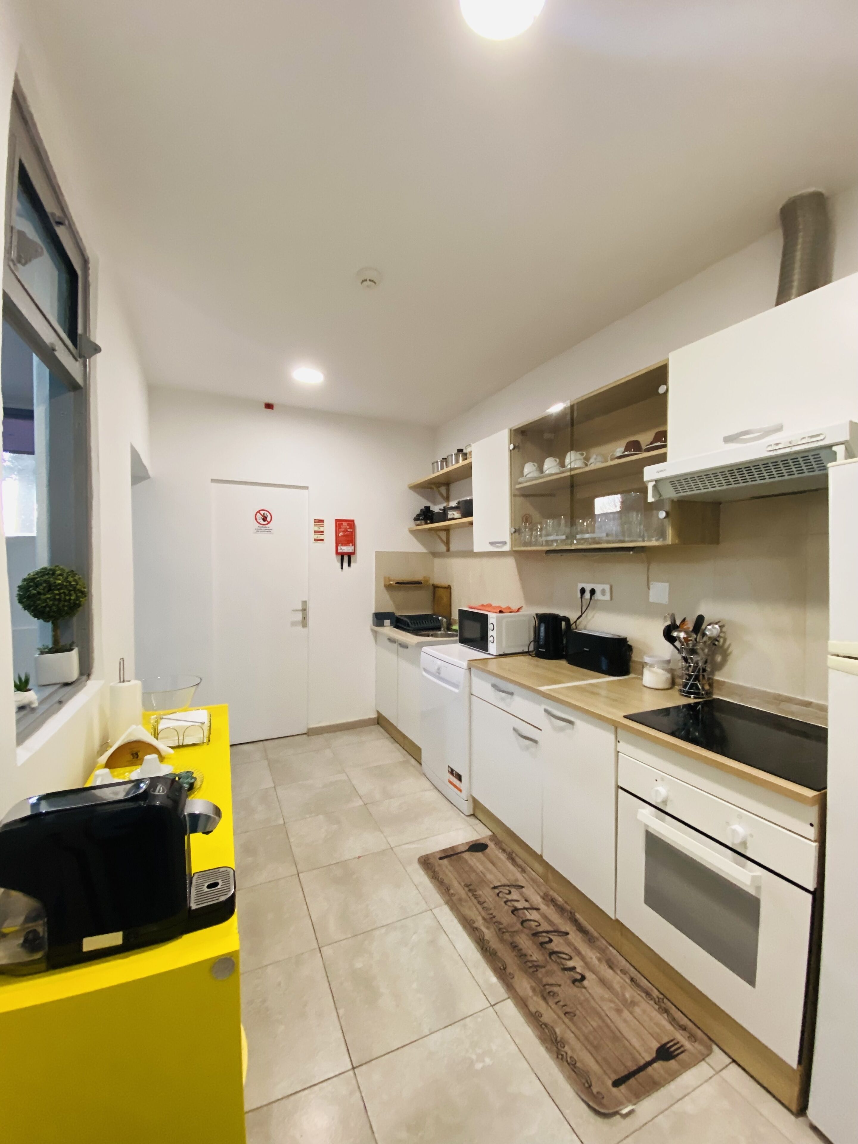 A compact kitchen with white cabinets, a yellow countertop, a microwave, a coffee maker, and a sink.