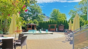 An outdoor patio area with wicker furniture, yellow umbrellas, and a gazebo. - Alga Baltic Resort (Swinoujscie)
